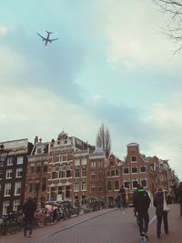 Low angle view of people on airplane in city against sky