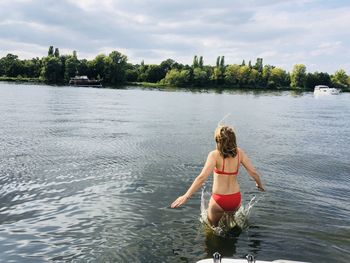 Rear view of woman jumping in lake