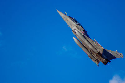 Low angle view of airplane flying against clear blue sky