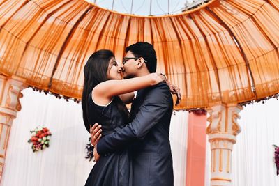 Side view of young wedding couple kissing while dancing in gazebo