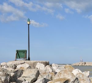 Lighthouse on rock by sea against sky