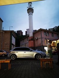 Cars on street by buildings in city against sky