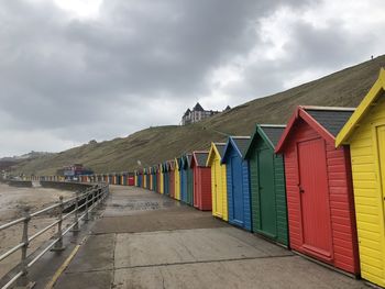 Beach huts by buildings against sky
