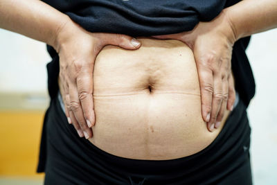 Midsection of woman standing by bare tree