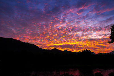 Scenic view of silhouette mountain against dramatic sky during sunset