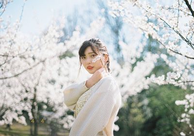 Portrait of a smiling young woman standing against trees