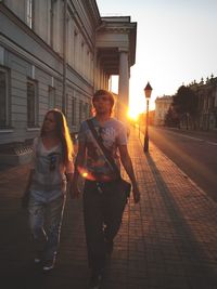 Woman standing on city street during sunset