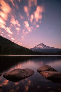 Scenic view of lake by mountains against sky during sunset