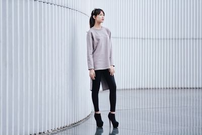 Full length of young woman standing by wall