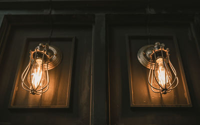 Low angle view of illuminated light bulb hanging on ceiling