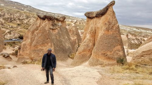 Full length of man standing by rock formations at badlands