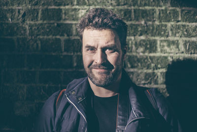 Portrait of smiling man against brick wall