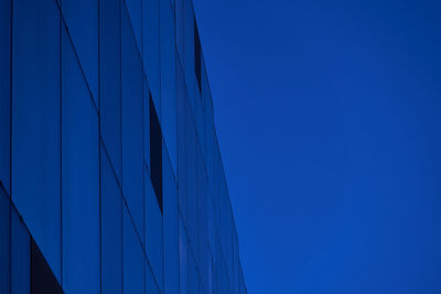 Low angle view of bridge and buildings against clear blue sky