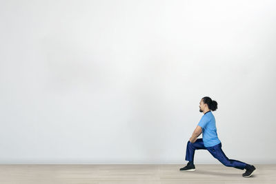 Side view of young man looking away against wall