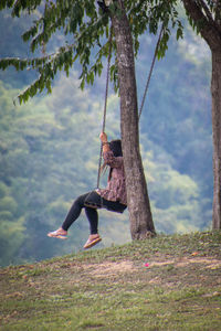 Low angle view of man climbing on tree trunk