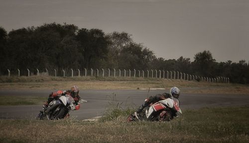 People riding motorcycle on field against sky