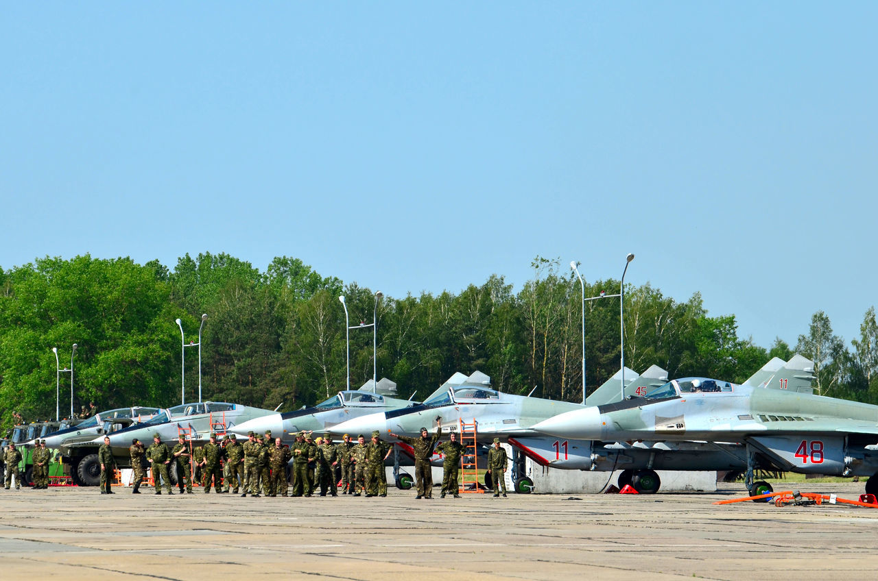 PEOPLE AT AIRPORT RUNWAY AGAINST SKY