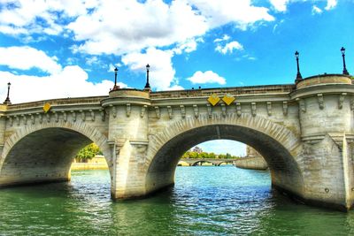 Low angle view of arch bridge over river against sky