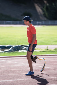 Side view of young athlete with prosthetic leg standing at sports track
