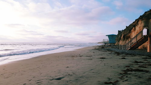 Scenic view of beach against cloudy sky at sunset