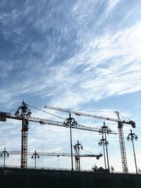 Low angle view of silhouette cranes against sky