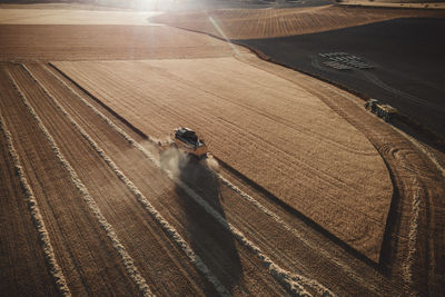 Combine harvester working at sunset from aerial view.