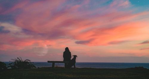 Silhouette woman standing by sea against sky during sunset