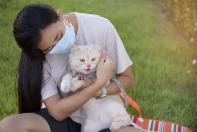 Side view of young woman holding cat