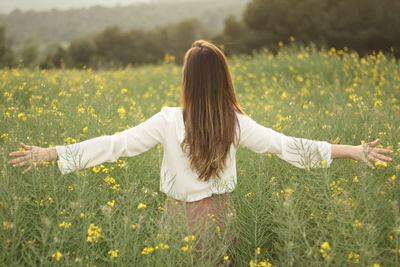 Rear view of woman with arms raised on field