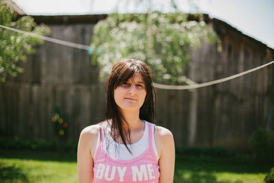 Portrait of woman wearing tank top with buy me written standing outdoors