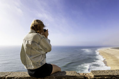 Rear view of woman looking at sea against sky