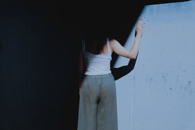 Rear view of woman standing by wall in darkroom