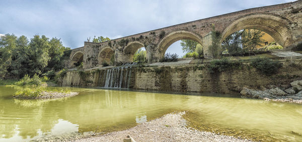 Arch bridge over river against sky