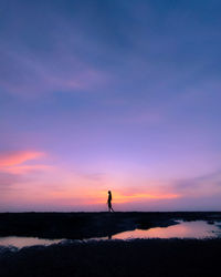 Silhouette man standing on beach against sky during sunset