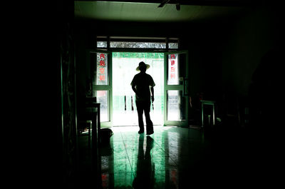 Silhouette man with hat walking in corridor