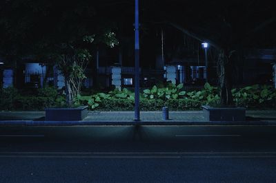 Empty road by buildings in city at night