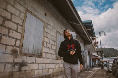 Full length of young man standing against brick wall