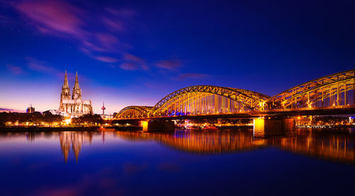 Reflection of illuminated bridge over river at night