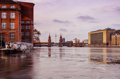 Boat on frozen lake against oberbaum bridge in city