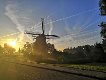 Traditional windmill on field against sky at sunset