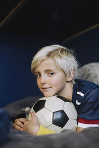 Portrait of boy with soccer ball in bedroom at home