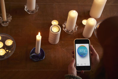 Woman lighting candles and using temperature app