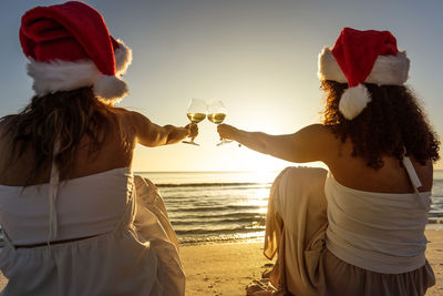 Rear view of women on beach against sky