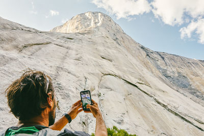 Young man taking picture of el capitan mountain in yosemite park.