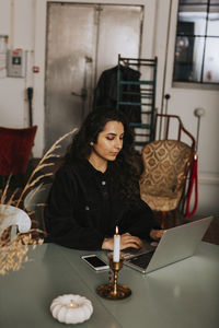 Young woman using phone while sitting on table