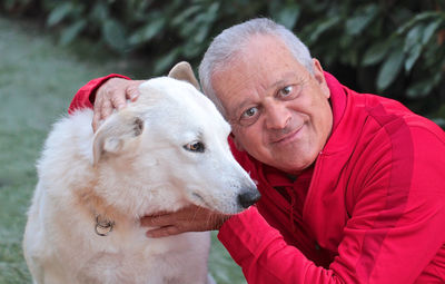 Close-up portrait of senior man petting dog at park