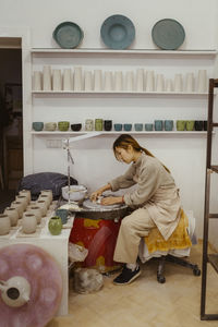 Side view of craftswoman working on pottery wheel at workshop