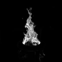 Close-up of burning candle against black background