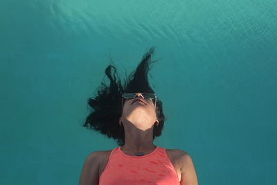 Portrait of young woman with arms raised in swimming pool