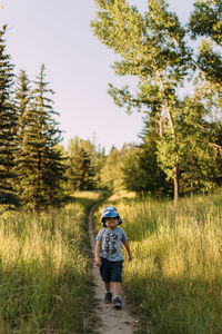 Rear view of boy walking on field